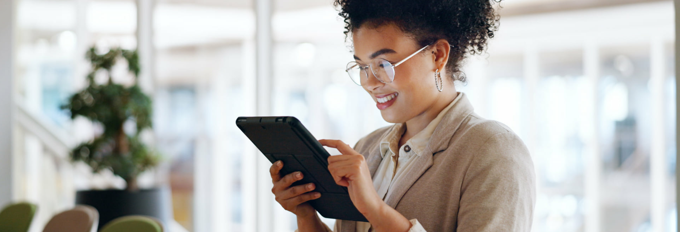 Frau mit Brille, beiger Blazer, Tablet, L&auml;cheln